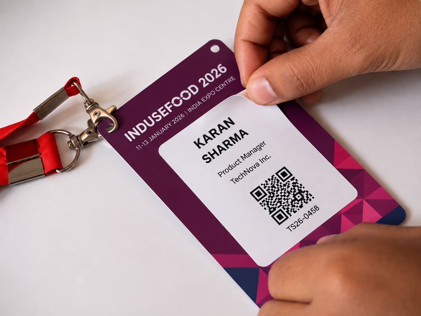A guest holding a real, printed Digi Swagat badge and lanyard for INDUSEFOOD 2026 at the India Expo Centre